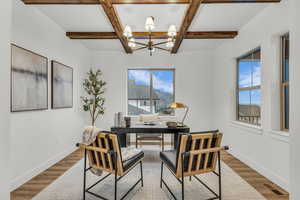 Home office featuring coffered ceiling, a chandelier, and wood finished floors