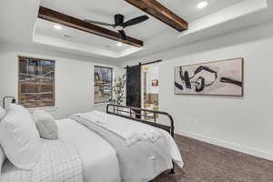 Carpeted bedroom with recessed lighting, a barn door, a ceiling fan, a raised ceiling, and connected bathroom