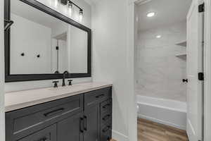 Bathroom featuring vanity, light wood-style flooring, recessed lighting, and bathtub / shower combination