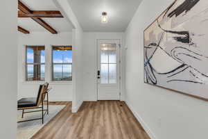 Entrance foyer with beamed ceiling and light wood-style flooring