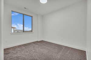 Spare room with baseboards and dark carpet