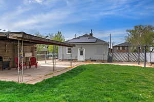 Rear view of property with roof mounted solar panels, a patio area, and a gate