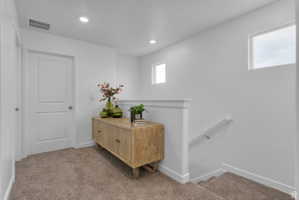 Hall with an upstairs landing, light carpet, and recessed lighting