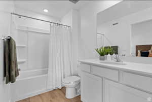 Bathroom with light wood-style flooring, vanity, and shower / bathtub combination with curtain