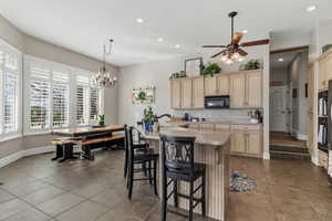 Kitchen featuring tasteful backsplash, a ceiling fan, light wood finish cabinetry, and black appliances