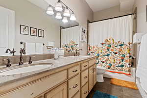 Full bathroom with double vanity and shower / bath combo with shower curtain
