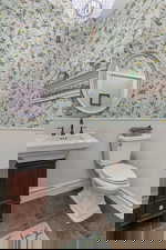 Half bath with wainscoting, vanity, and wallpapered walls