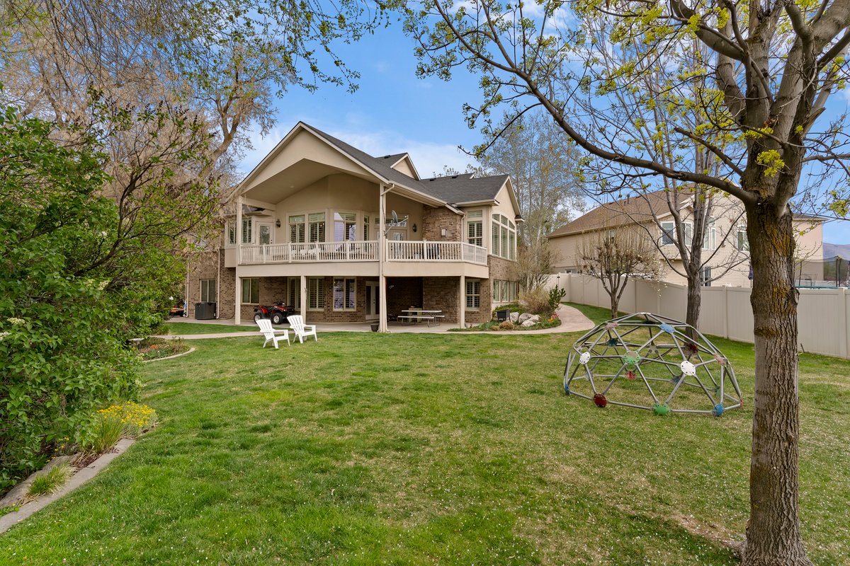 Back of property featuring a patio, brick siding, a balcony, and a playground