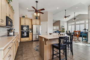 Kitchen with ceiling fan, black appliances, a breakfast bar, light countertops, and recessed lighting