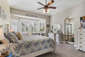 Bedroom with carpet, arched walkways, a ceiling fan, and connected bathroom