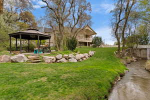 View of green lawn with a gazebo, a water view, and a patio