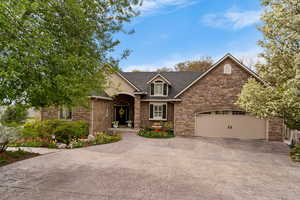 Traditional-style home featuring concrete driveway, stone siding, an attached garage, and roof with shingles