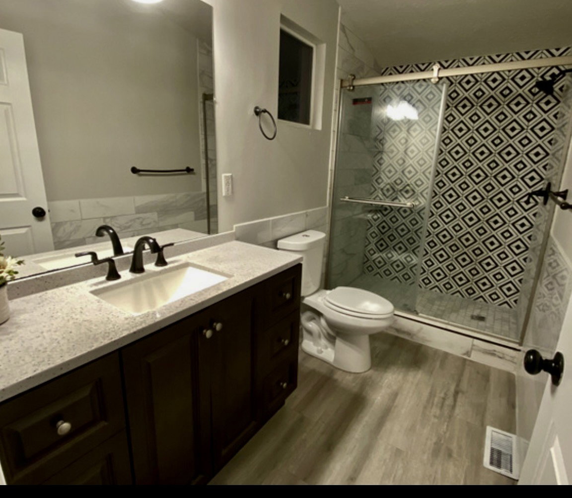 Full bath with vanity, a shower stall, and dark wood-style floors