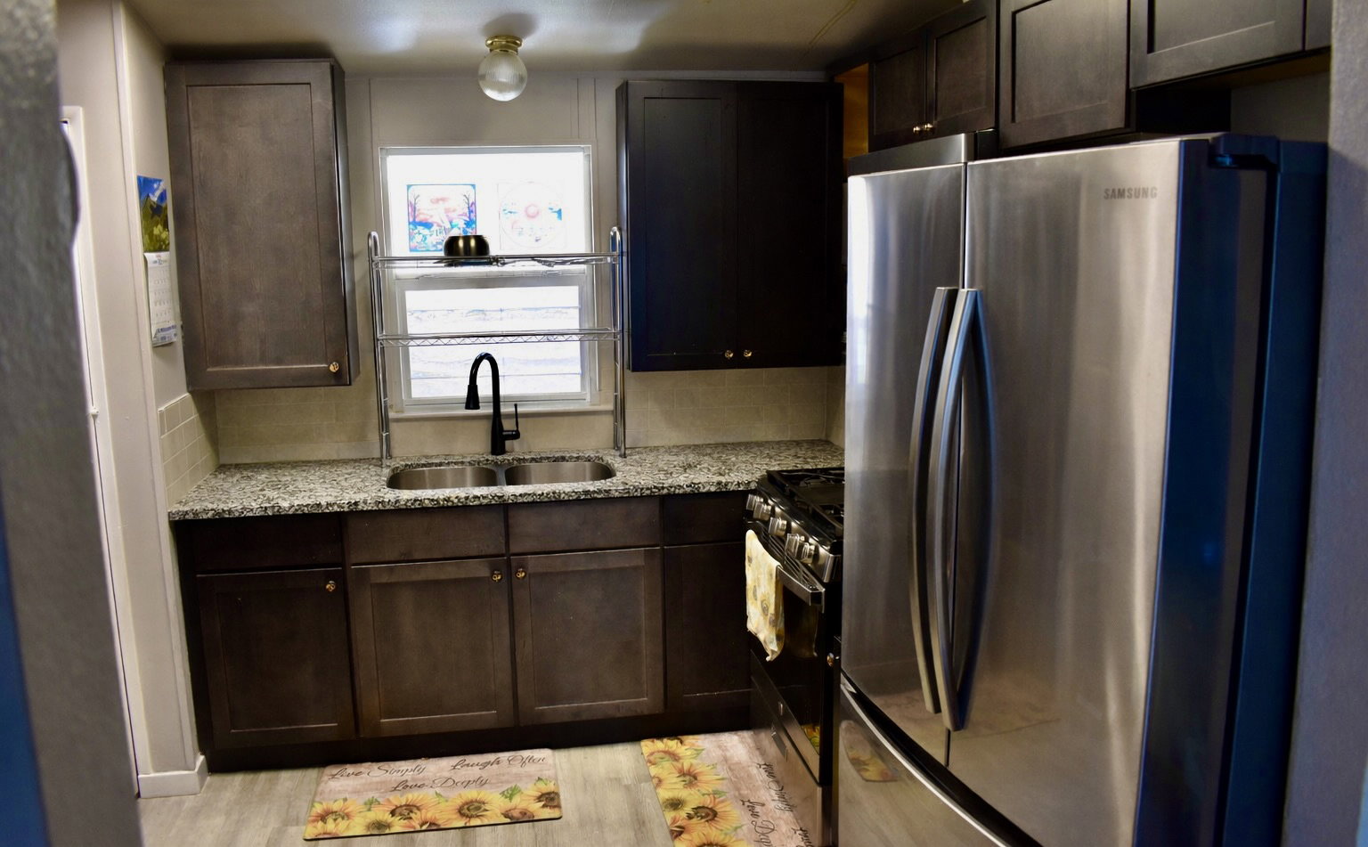 Kitchen with stainless steel appliances, light stone countertops, dark wood finish cabinetry, and tasteful backsplash