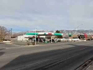 View of asphalt street featuring a mountain view, street lighting, curbs, and sidewalks