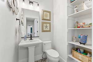 Half bathroom with toilet and baseboards