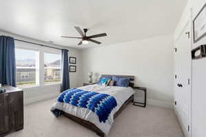 Bedroom featuring a closet, light colored carpet, and a ceiling fan
