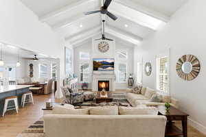 Living area featuring a warm lit fireplace, ceiling fan, light wood-style floors, and recessed lighting