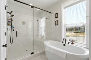 Bathroom with a shower stall, a freestanding bath, healthy amount of natural light, and light tile patterned floors