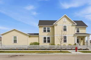 View of front of home with board and batten siding, roof with shingles, and a fenced front yard