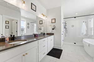 Bathroom featuring a soaking tub, double vanity, a stall shower, light tile patterned floors, and recessed lighting