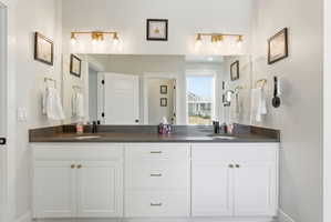 Full bathroom with double vanity and baseboards