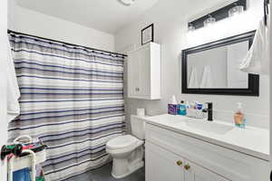 Full bath with curtained shower, vanity, and dark tile patterned floors