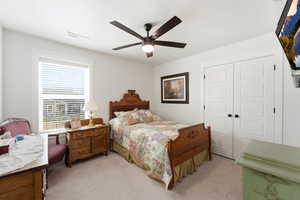 Bedroom featuring light colored carpet, a closet, and ceiling fan