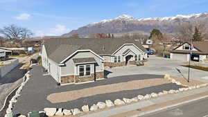 View of front of property with stone stucco siding, a shingled roof, a mountain view
