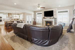 Living area featuring arched walkways, ceiling fan, recessed lighting, a stone fireplace, and dark wood-type flooring