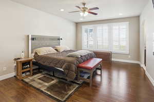 Primary bedroom with wood finished floors, a ceiling fan, recessed lighting, large windows and arched walkways