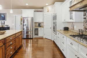 Kitchen with stainless steel appliances, dark wood-style floors, hanging light fixtures, wine cooler, and light granite counters
