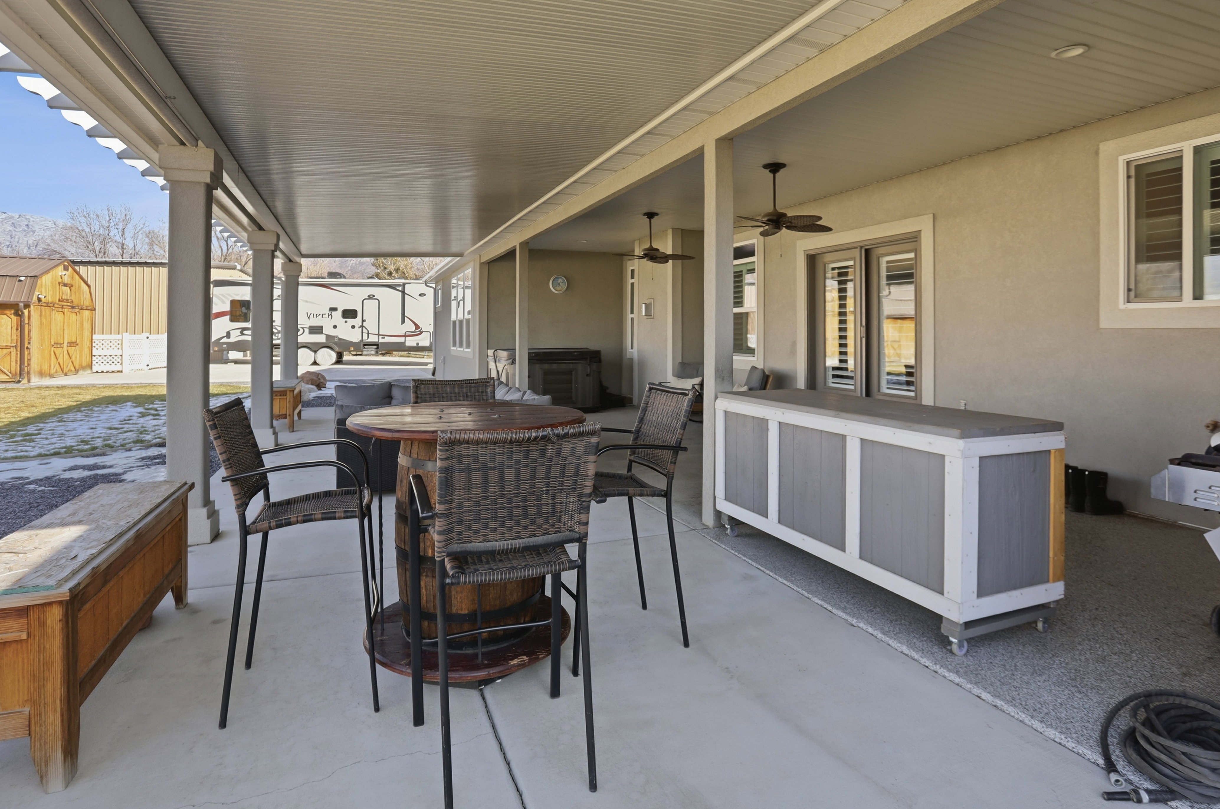 View of patio / terrace with outdoor dining space, a ceiling fan, hot tub and a shed