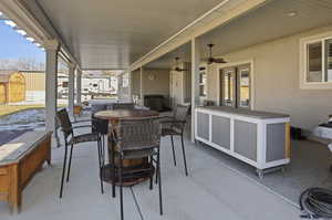 View of patio / terrace with outdoor dining space, a ceiling fan, hot tub and a shed