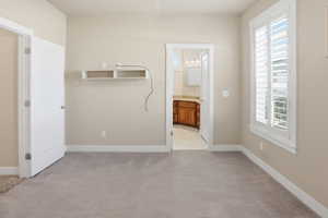 Unfurnished bedroom with light colored carpet and ensuite bath