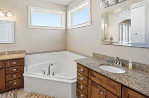 Full bath featuring two vanities, a garden tub, and healthy amount of natural light