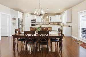 Dining room with dark wood-style floors and hanging lights