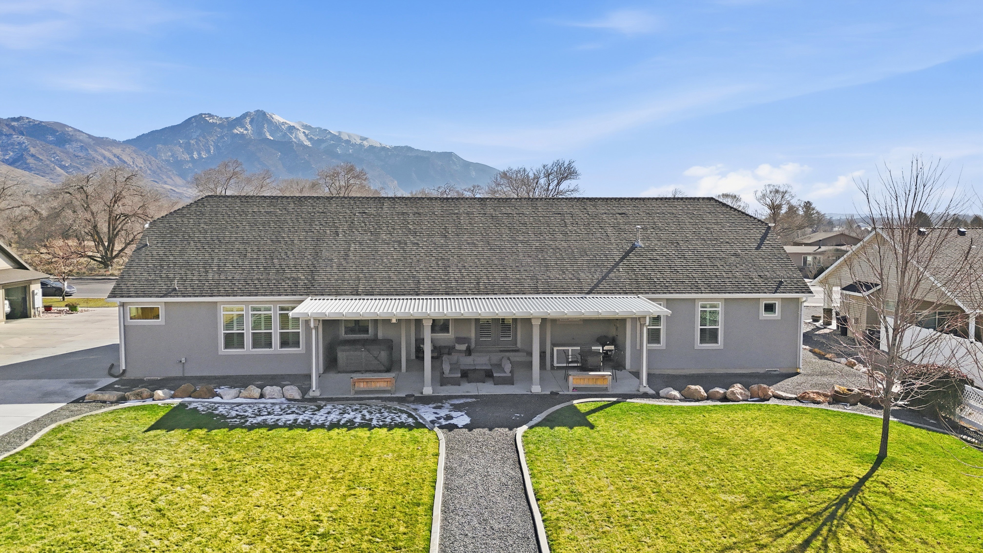 Back of house featuring a yard, a shingled roof, a patio area, and stucco siding