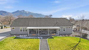 Back of house featuring a yard, a shingled roof, a patio area, and stucco siding
