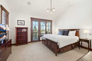 Bedroom with vaulted ceiling, access to exterior, and light colored carpet