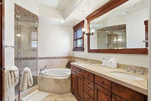 Bathroom featuring double vanity, a stall shower, a garden tub, and light tile patterned floors