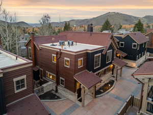 Back of house at dusk with a patio, a mountain view, and stone siding