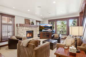 Living area with a stone fireplace, recessed lighting, and light colored carpet