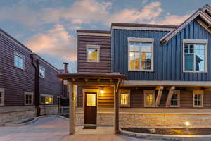 View of front facade with board and batten siding, stone siding, and a porch