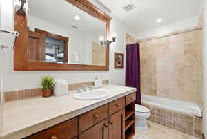 Ensuite bathroom with vanity, tiled shower / bath, light tile patterned floors, and recessed lighting