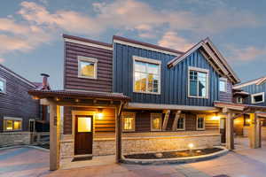 View of front of property featuring board and batten siding, stone siding, and covered porch