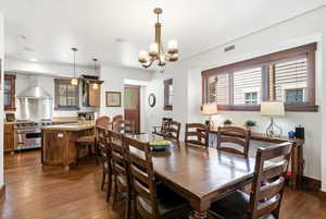 Dining area featuring dark wood-style flooring and a chandelier