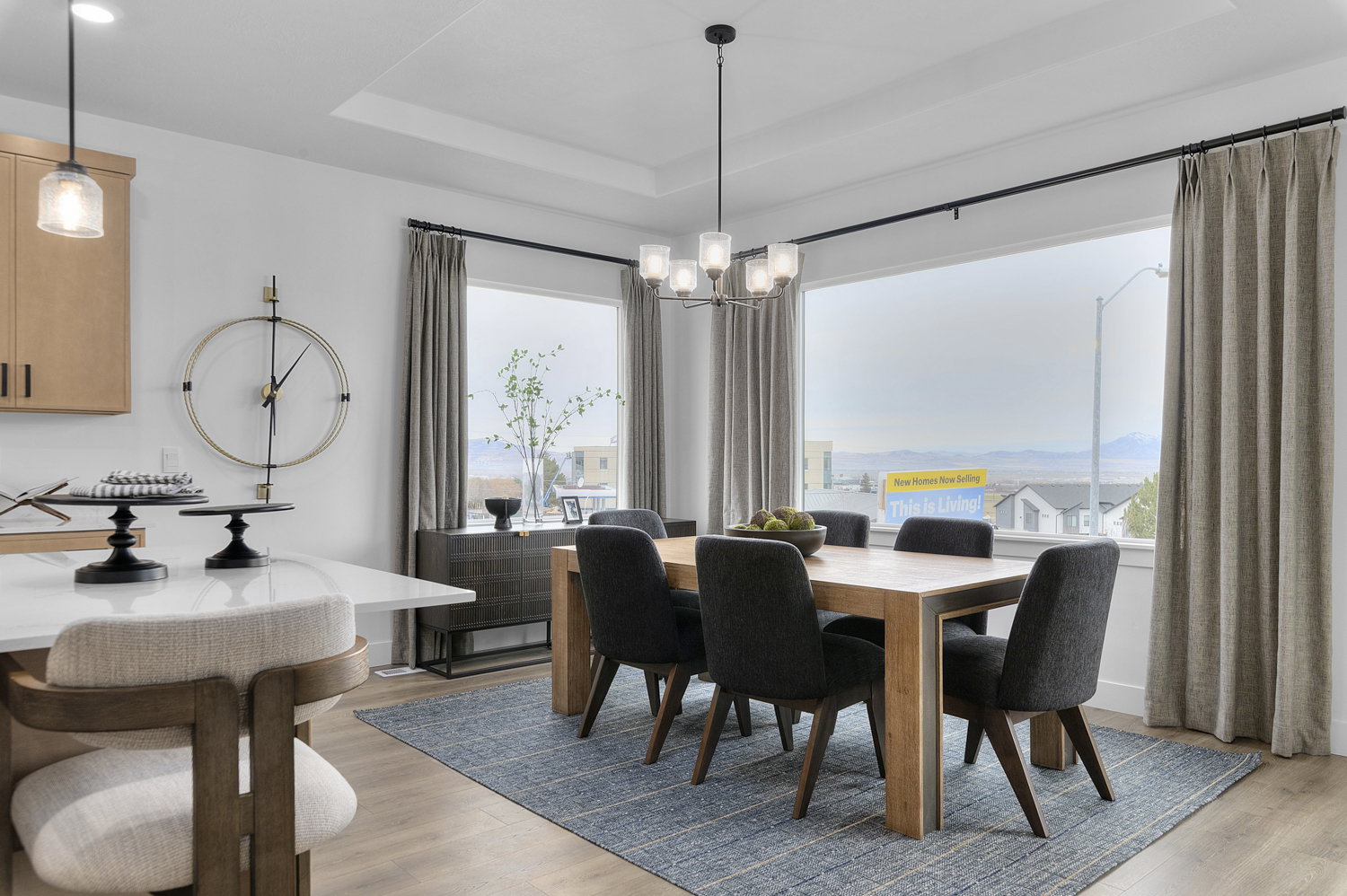 Dining space with light wood-style flooring, a raised ceiling, and hanging lights