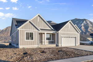 View of front of property with a mountain view, covered porch, driveway, an attached garage, and roof with shingles