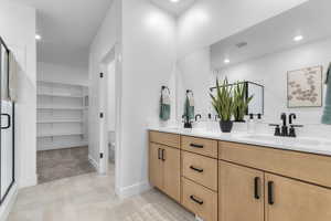 Bathroom featuring a walk in closet, double vanity, light tile patterned floors, a shower stall, and recessed lighting
